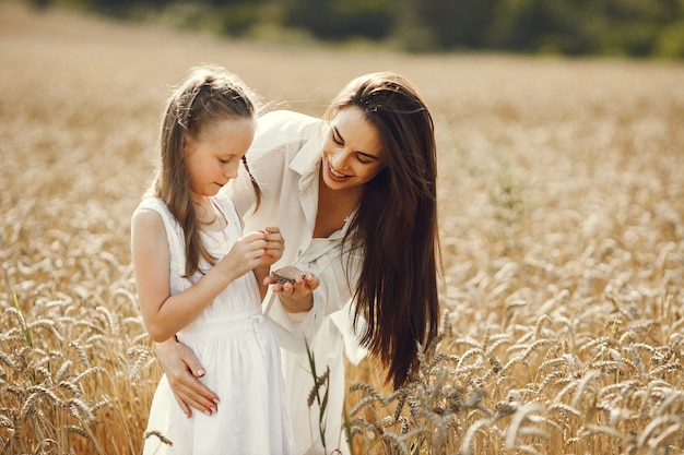 giovane madre e sua figlia in abiti bianchi al campo di grano in una giornata di sole.