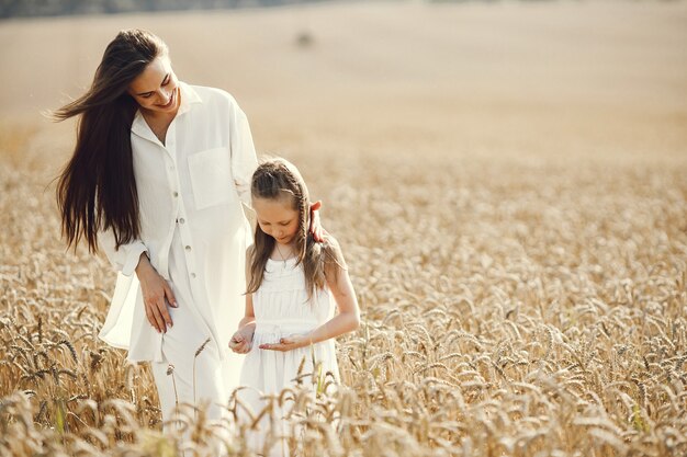 giovane madre e sua figlia in abiti bianchi al campo di grano in una giornata di sole.