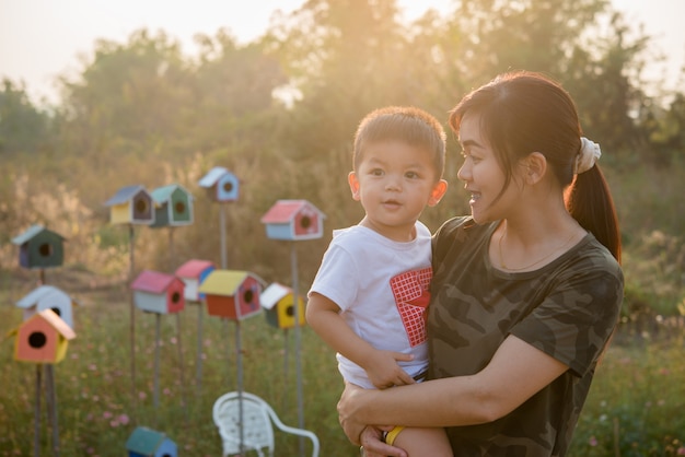 Giovane madre felice che gioca e che si diverte con il suo piccolo figlio del bambino nel parco un giorno di estate soleggiato