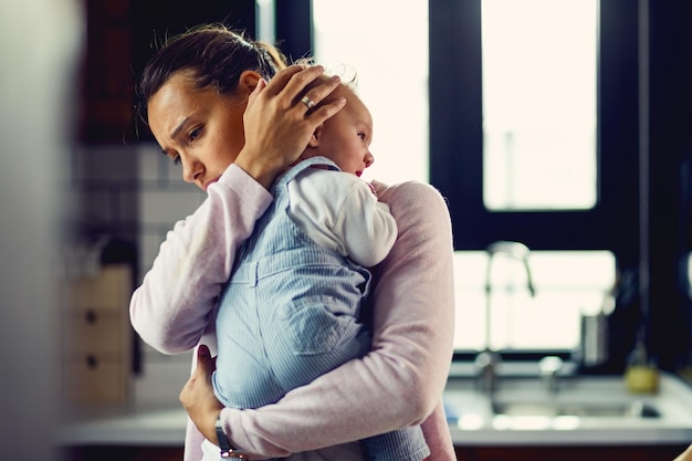 Giovane madre preoccupata che conforta il suo bambino che piange a casa