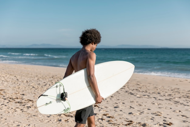 Giovane maschio afroamericano che va praticando il surfing