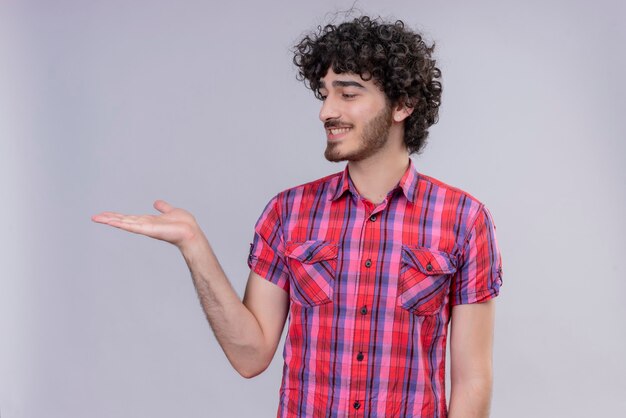 Giovane maschio capelli ricci isolato camicia colorata con elemento di segno