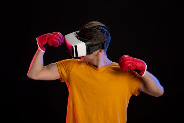 Giovane maschio che gioca la realtà virtuale in guanti di mma sulla superficie scura