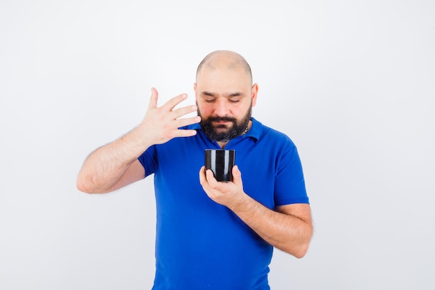 Giovane maschio che guarda dentro la tazza nella vista frontale della camicia blu.