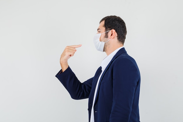 Giovane maschio che punta alla sua maschera medica in camicia