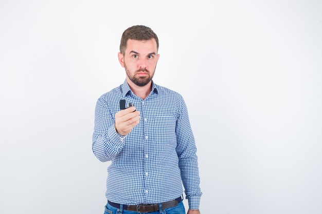 Giovane maschio che tiene più leggero in camicia, jeans e che sembra fiducioso. vista frontale.