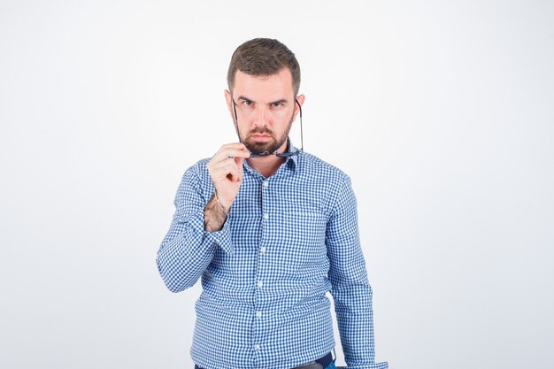 Giovane maschio con gli occhiali in camicia, jeans e guardando fiducioso. vista frontale.