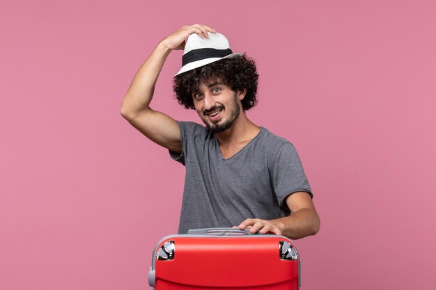 Giovane maschio di vista frontale che si prepara per il viaggio e che tiene il cappello sullo spazio rosa