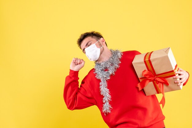 Giovane maschio di vista frontale che tiene il natale presente nella maschera sterile