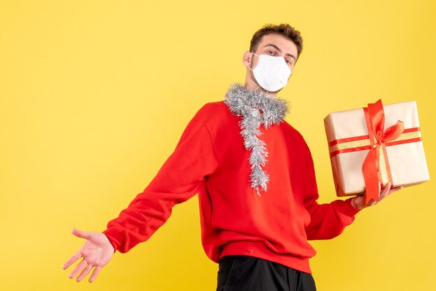 Giovane maschio di vista frontale che tiene il natale presente nella maschera sterile