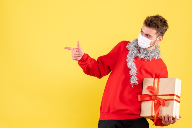 Giovane maschio di vista frontale che tiene il natale presente nella maschera sterile