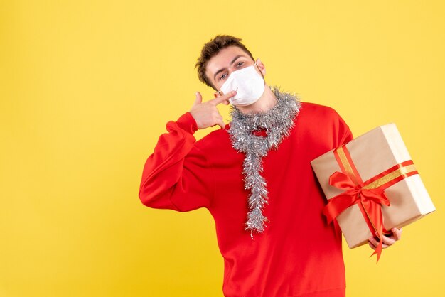 Giovane maschio di vista frontale che tiene il natale presente nella maschera sterile