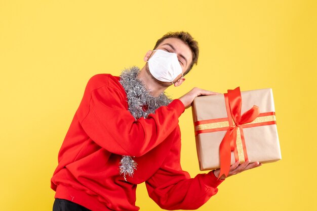 Giovane maschio di vista frontale che tiene il natale presente nella maschera sterile