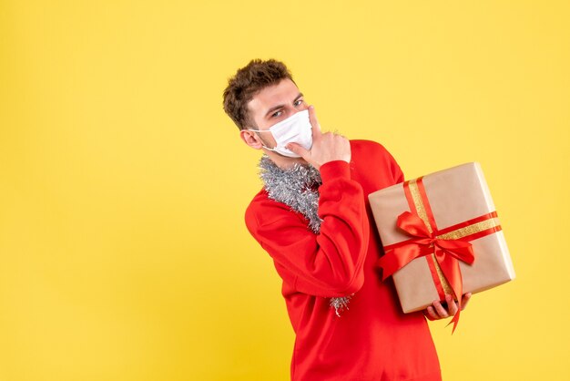 Giovane maschio di vista frontale che tiene il natale presente nella maschera sterile