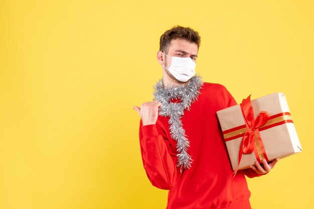 Giovane maschio di vista frontale che tiene regalo di Natale in maschera sterile