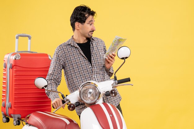 Giovane maschio di vista frontale con la bici e la mappa della tenuta della borsa sul giallo