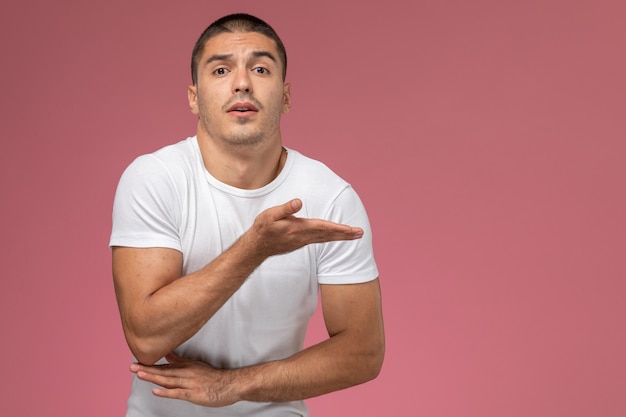 Giovane maschio di vista frontale in camicia bianca con la mano alzata sui precedenti rosa