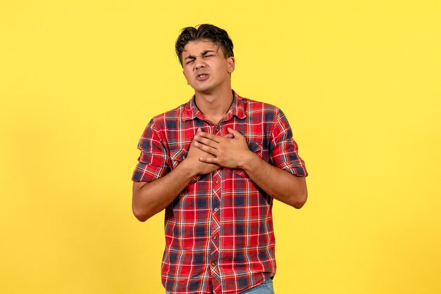 Giovane maschio di vista frontale in camicia luminosa che posa sul colore del modello maschio del fondo giallo