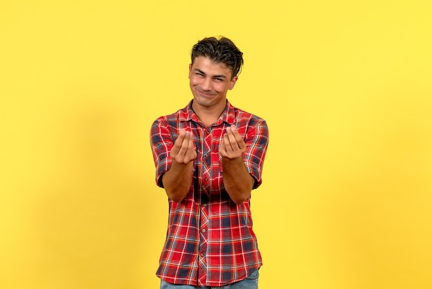 Giovane maschio di vista frontale in camicia luminosa che posa sul colore del modello maschio del fondo giallo