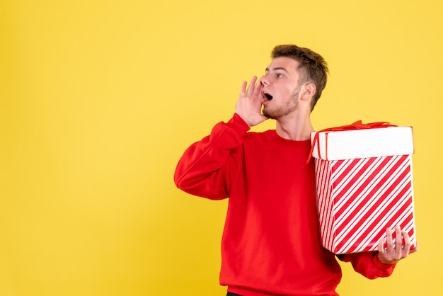 Giovane maschio di vista frontale in camicia rossa con la chiamata del regalo di Natale