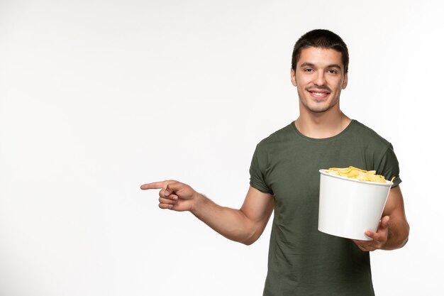 Giovane maschio di vista frontale in maglietta verde con le patatine fritte e sorriso sul cinema di film solitario della persona del film della parete bianca