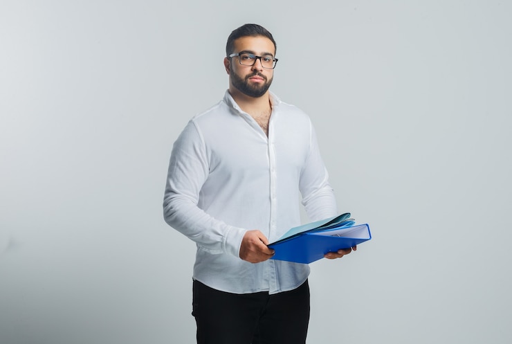 Foto gratuito giovane maschio in camicia bianca, pantaloni che tengono le cartelle e che sembrano fiduciosi
