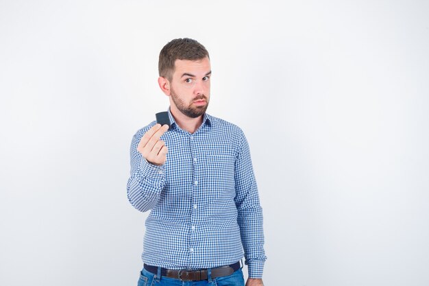 Giovane maschio in camicia, jeans che tengono più leggero e che sembra fiducioso, vista frontale.