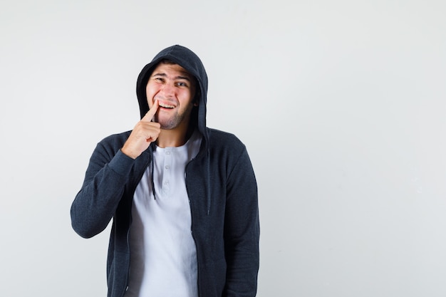 Giovane maschio in t-shirt, giacca che soffre di mal di denti e sembra a disagio, vista frontale.