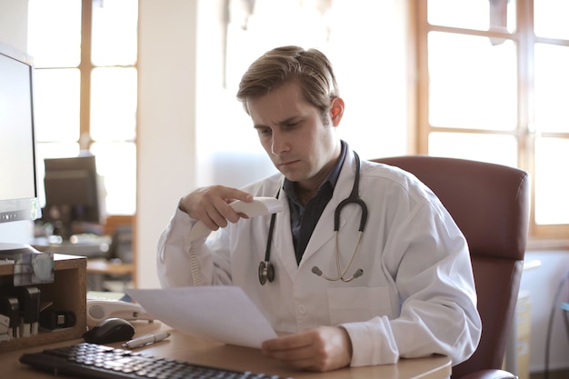 Giovane medico che lavora nel suo ufficio con finestre sullo sfondo