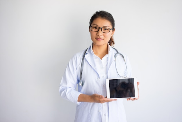 Giovane medico femminile asiatico contento che mostra lo schermo di computer della compressa.