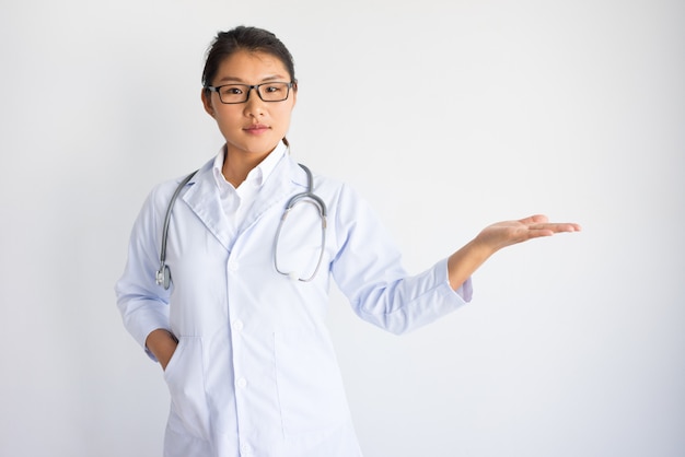 Giovane medico femminile asiatico contenuto che tiene spazio vuoto sulla palma.