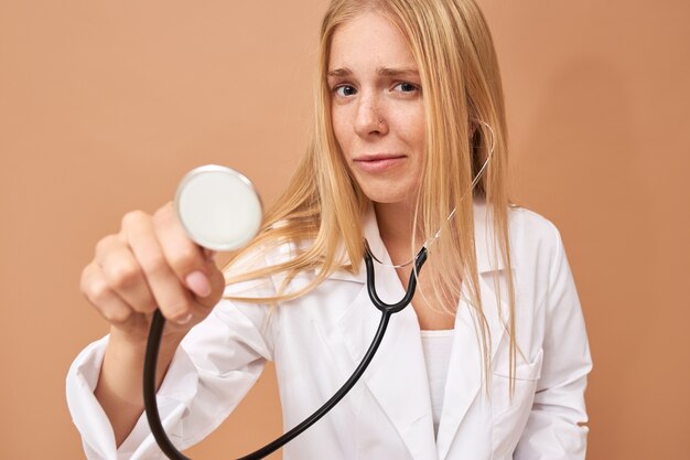 Giovane medico femminile con capelli biondi diritti facendo uso dello stetoscopio