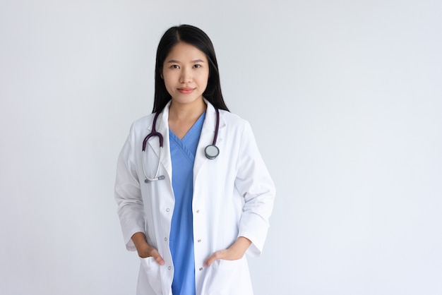 Giovane medico femminile contento che posa alla macchina fotografica