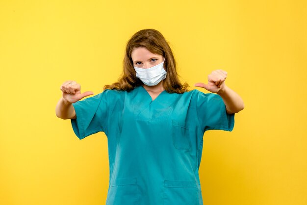 Giovane medico femminile di vista frontale in maschera sullo spazio giallo chiaro