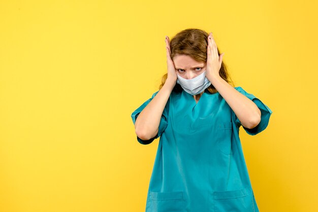 Giovane medico femminile di vista frontale in maschera sullo spazio giallo