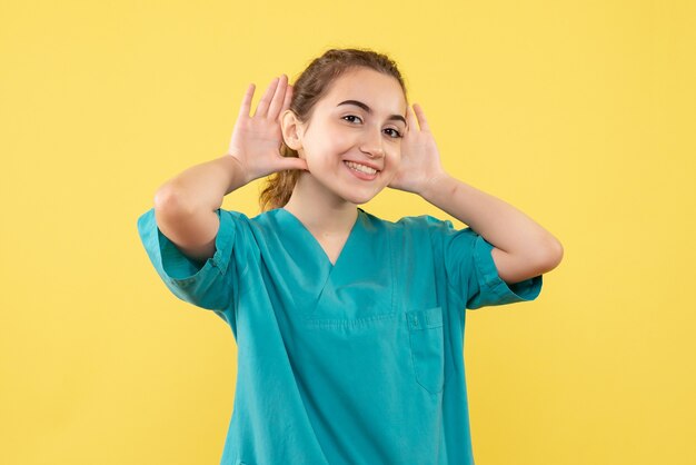 Giovane medico femminile di vista frontale in vestito medico su priorità bassa gialla