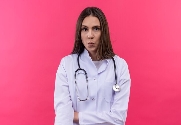 giovane medico ragazza indossa stetoscopio abito medico che mostra il gesto di bacio sul muro rosa isolato
