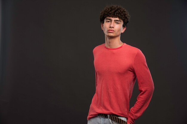 Giovane modello con i capelli ricci che mette le mani in tasca.