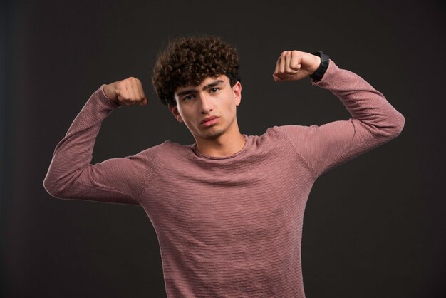 Giovane modello con i capelli ricci che mostrano i suoi muscoli.