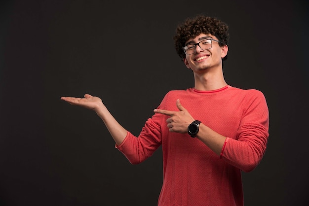 Giovane modello con i capelli ricci che promuovono qualcosa.