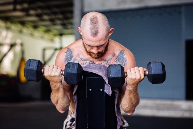 Giovane muscoloso tatuato forte muscolo barbuto uomo europeo facendo duro esercizio