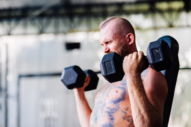 Giovane muscoloso tatuato forte muscolo barbuto uomo europeo facendo duro esercizio