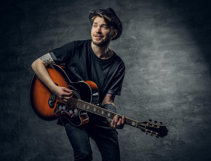 Foto gratuito giovane musicista alla moda hipster blues e jazz acustico con tatuaggi sulle braccia che suonano melodia.