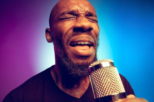 Giovane musicista jazz afro-americano che canta una canzone sul gradiente viola-blu