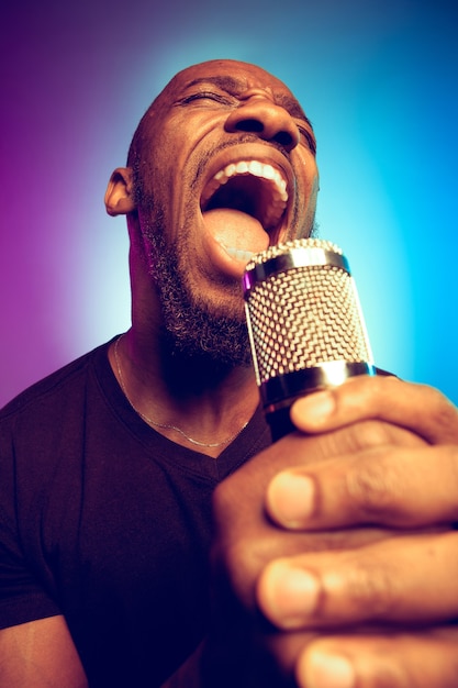 Giovane musicista jazz afro-americano che canta una canzone sul gradiente viola-blu
