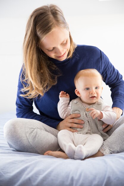 Giovane nuova mamma allegra che tiene il suo piccolo bambino sveglio