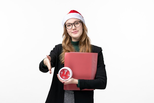 Giovane orologio femminile della tenuta di vista frontale e file sulla lezione del libro dell'università della parete bianca