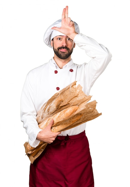 Giovane panettiere in possesso di un po &#39;di pane e fare segno stupido