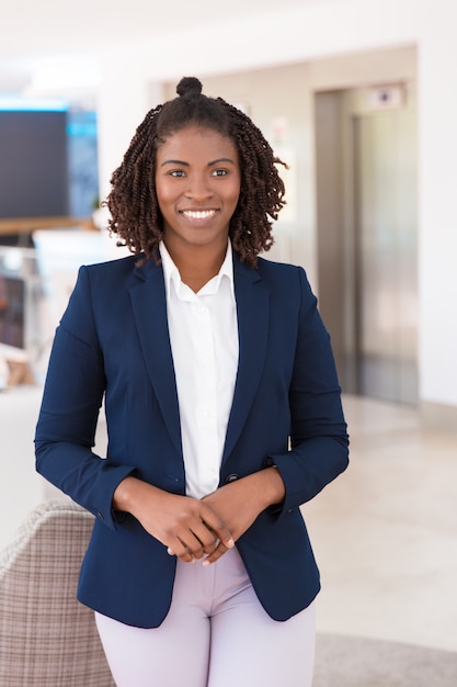 Giovane professionista femminile felice che posa nel corridoio dell'ufficio