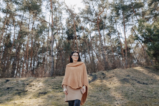 Giovane ragazza alla moda attraente sulla natura sullo sfondo della foresta con il telefono in una giornata di sole